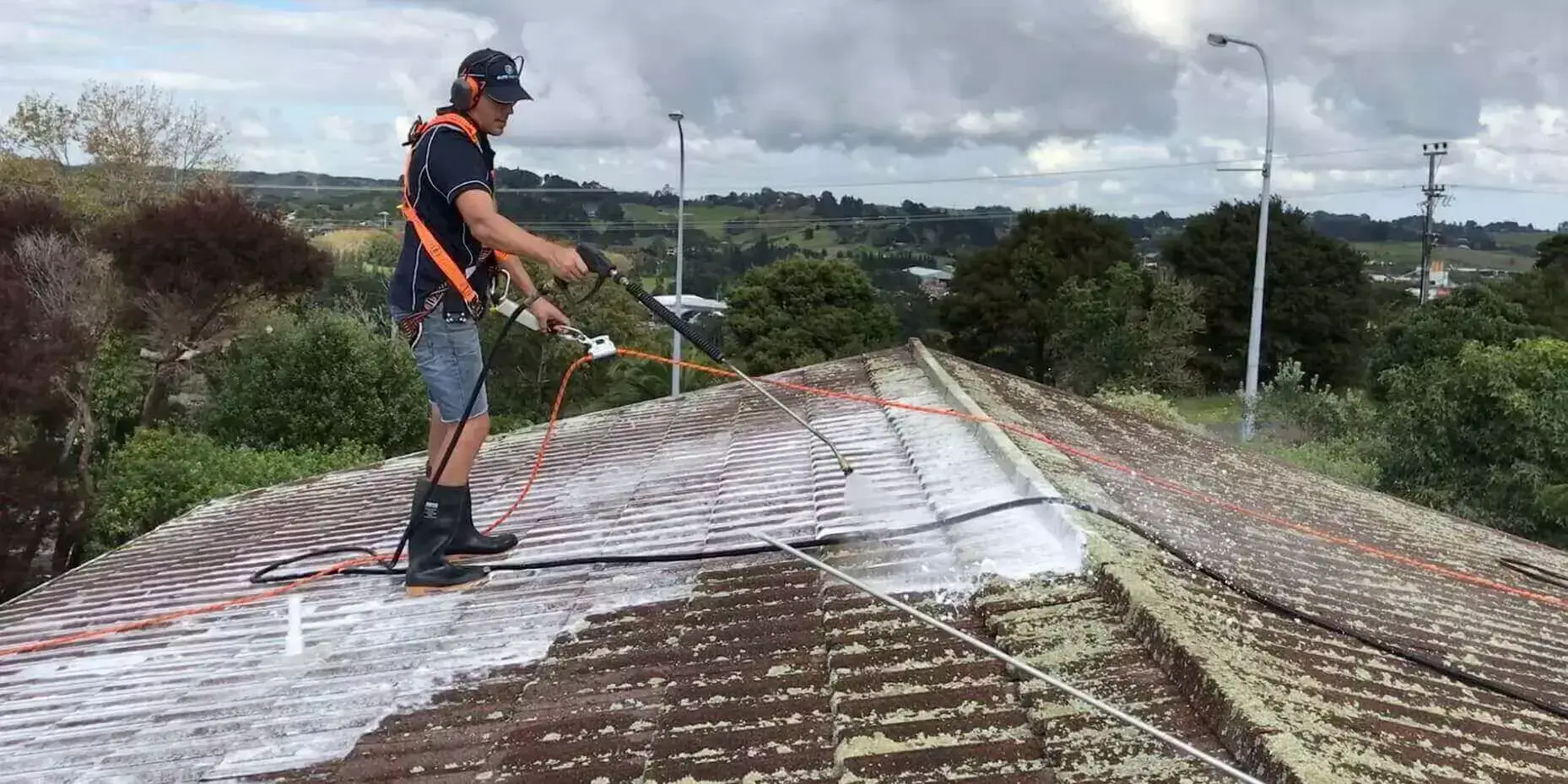 A Man Cleaning Roof Using High Water Pressure Image
